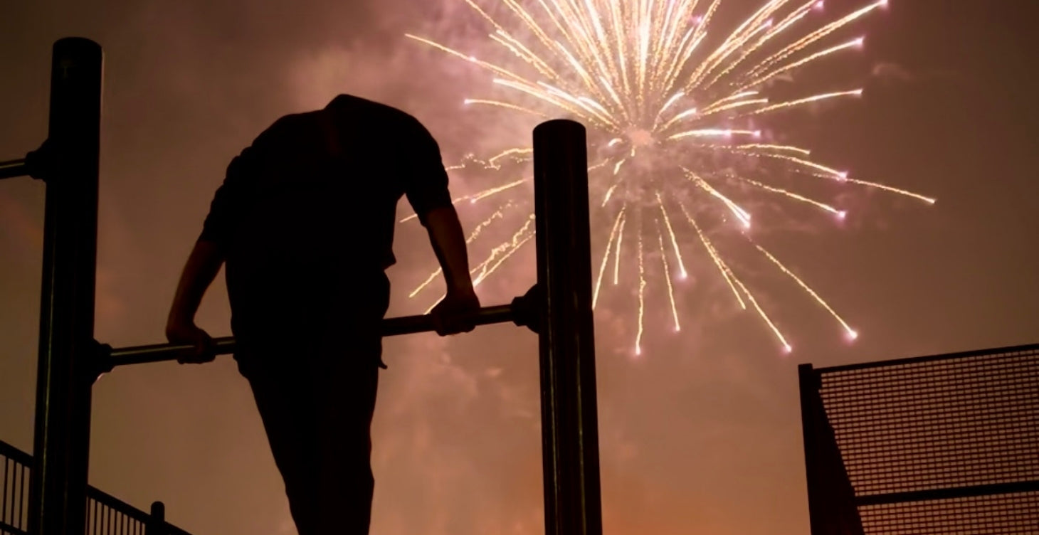 footer image of calisthenics athlete doing a muscle up with fireworks in the background. Calisthenics HQ